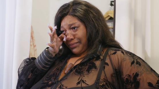 Woman crying, wiping tears from her eyes.