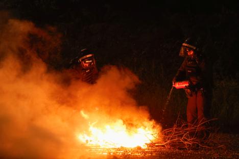 Riot police officers extinguishing a fire during a protest.