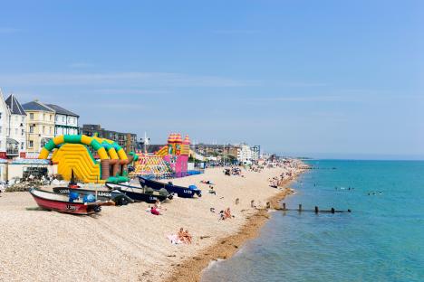 Beach scene in Bognor Regis with inflatable attractions and people sunbathing.
