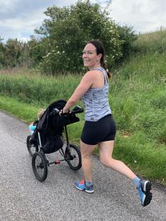 Woman jogging while pushing a stroller.