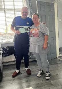 Couple holding ultrasound photo announcing pregnancy.