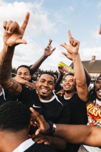 Group of men celebrating, arms raised.