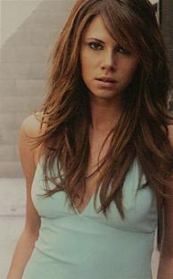 Woman with long brown hair wearing a light blue top.