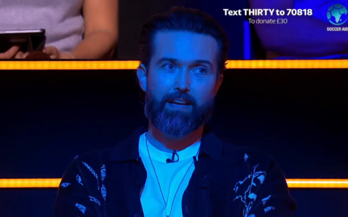 Man speaking on a dark blue stage, text overlay shows donation information for Soccer Aid.
