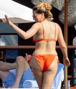 Stacey Solomon by a pool in an orange bikini.