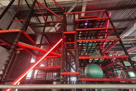 Multi-level indoor play structure with large green balls.