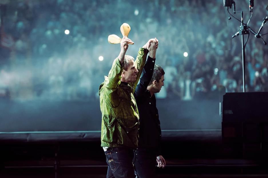 Noel and Liam Gallagher on stage at a concert.