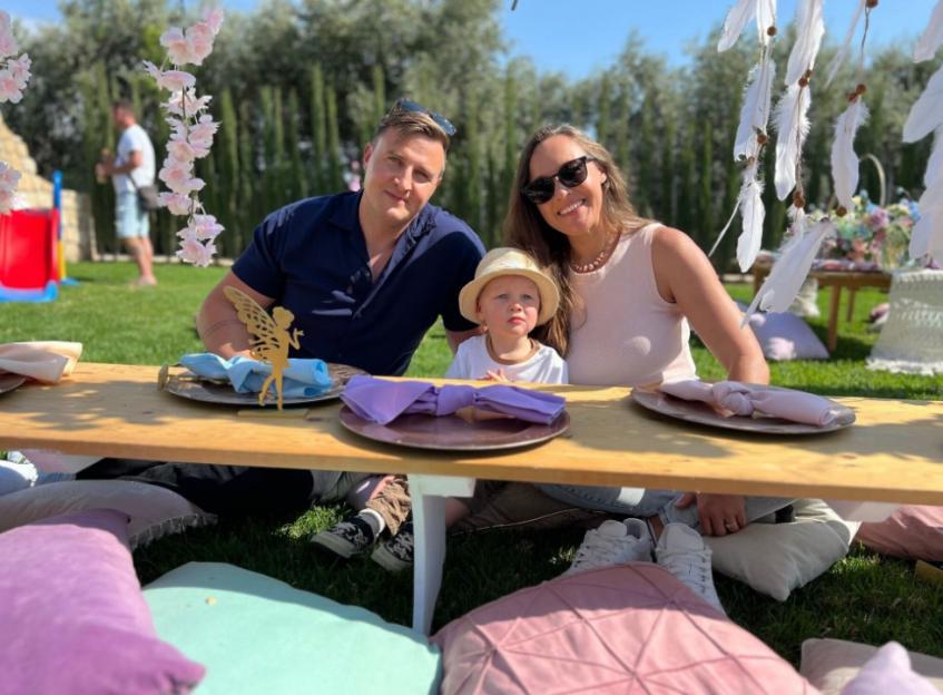 Family with young child at picnic table.