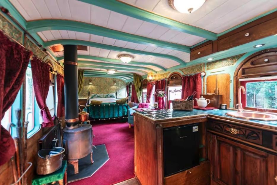 Interior of a restored 1895 GWR railway carriage, showing a bedroom, kitchenette, and bathroom.
