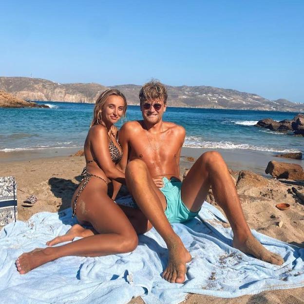 Couple sitting on a beach towel on a sandy beach.
