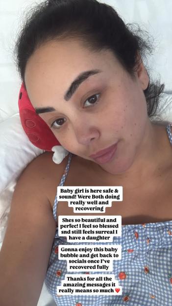 Postpartum woman lying in bed, announcing the birth of her baby girl.