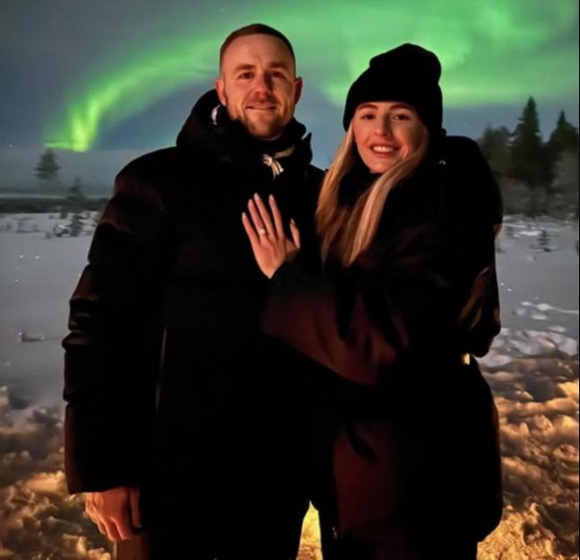 Couple embracing in front of the Northern Lights.