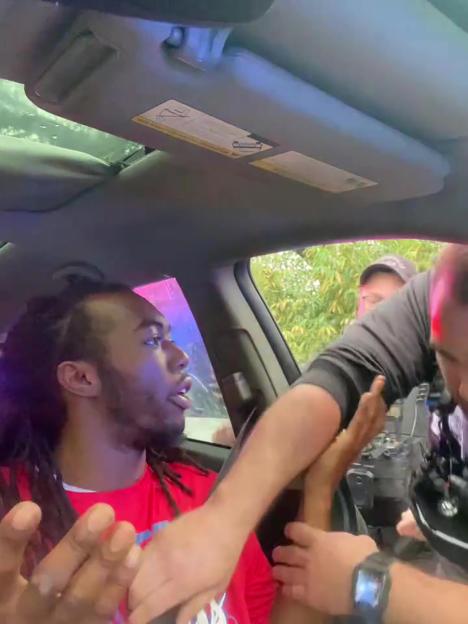 Police officer arresting a man in his car.