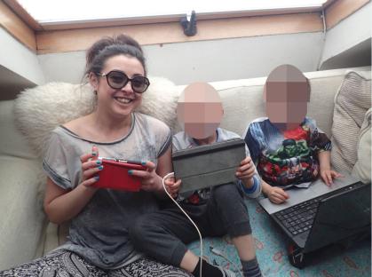 A woman and two children using tablets and a laptop.