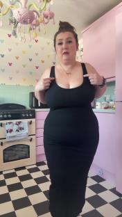 Woman in a black dress in her kitchen.