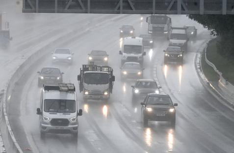 Cars driving on a rain-slicked highway.