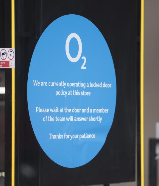 O2 store sign: locked door policy, wait for assistance.