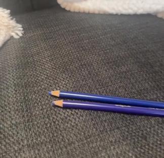 Two colored pencils on a gray couch.