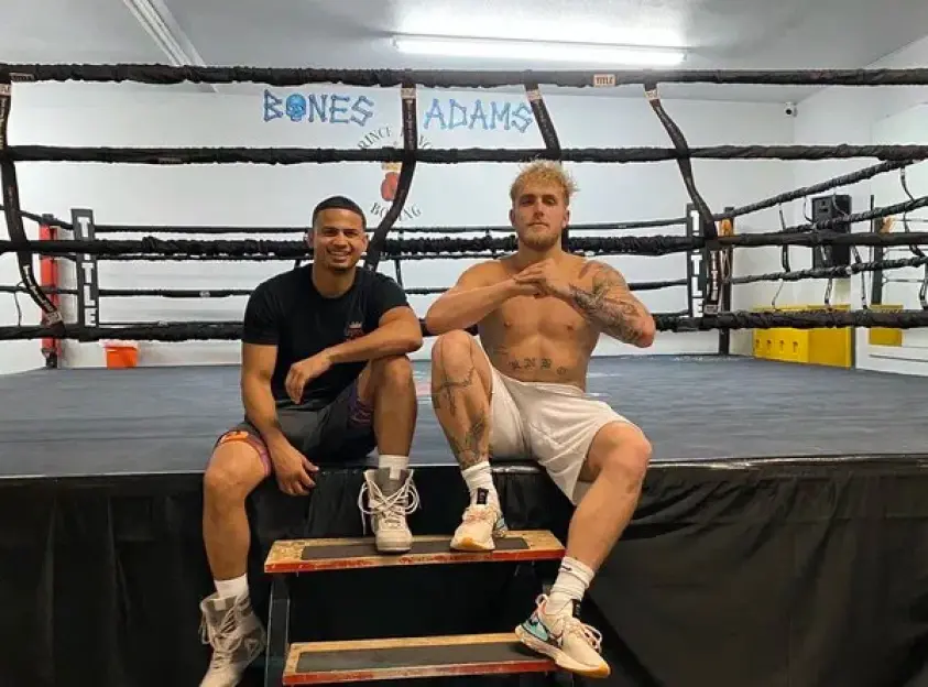 Two men sitting on steps in a boxing ring.