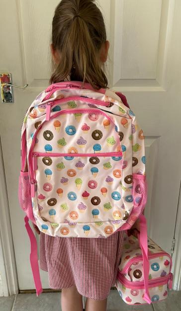 Girl wearing a pink donut backpack and lunchbox.
