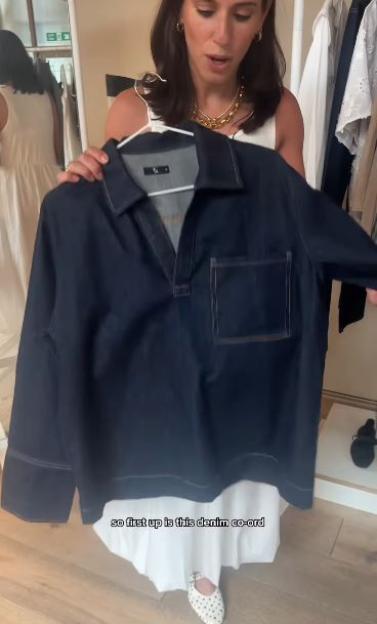 Woman holding up a dark denim shirt.