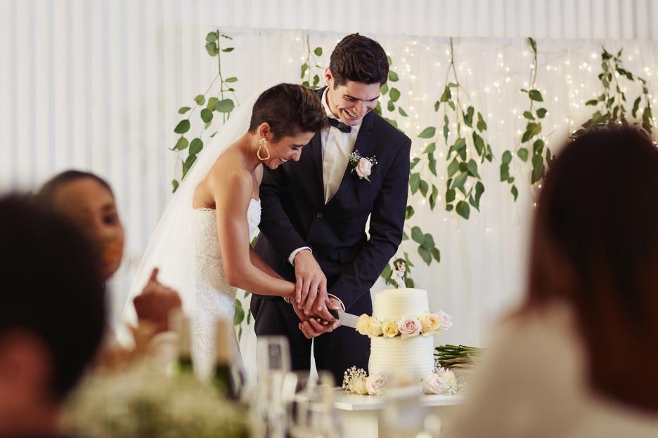 A happy couple cutting their wedding cake.