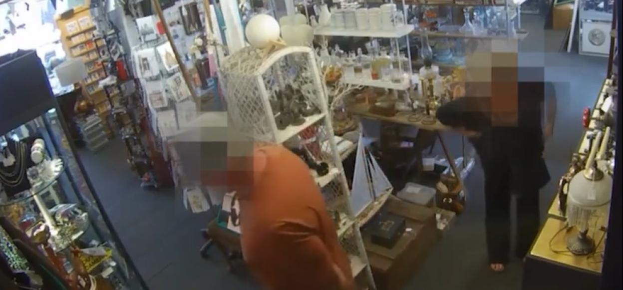 Security camera footage of a shop interior showing two people browsing.