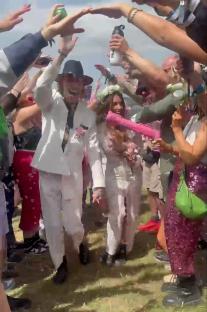 A couple getting married at a festival, surrounded by cheering people.