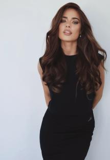 Portrait of a woman with long brown hair wearing a black dress.