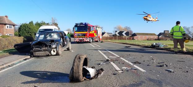 Aftermath of a car crash with a damaged Mini Cooper, a firetruck, and an air ambulance.