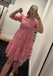 Woman giving a thumbs down while wearing a pink floral dress.