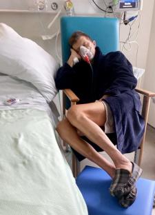 Man in hospital bed wearing oxygen mask.