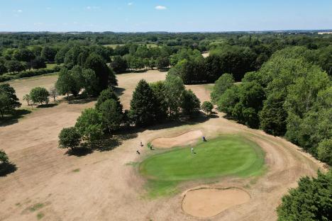 Aerial view of golfers on a dry golf course.