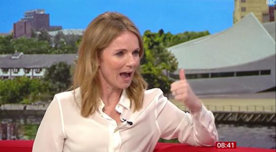 A woman gives a thumbs up during a television interview.
