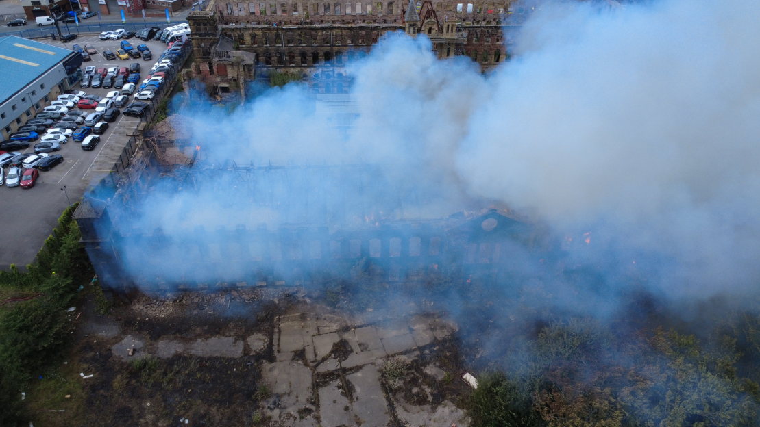 Aerial view of a building fire with smoke billowing from the ruins.
