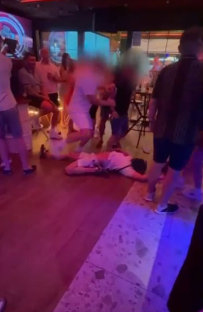 Person lying on the floor in a crowded bar.