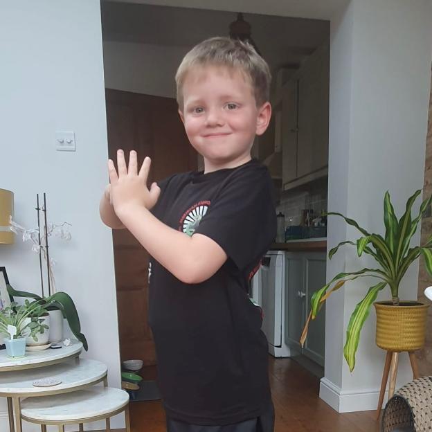 Young boy with hands up, smiling.