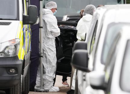 Forensic officers investigating a body found in a car.