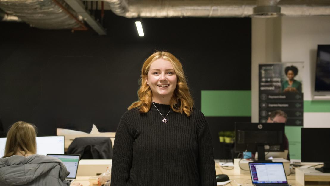Woman in a black sweater in an office setting.