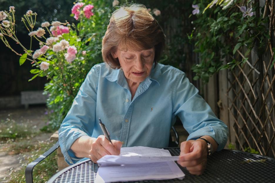 A woman sits outdoors reviewing paperwork.