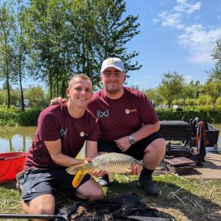 Two men holding a large carp they caught while fishing.