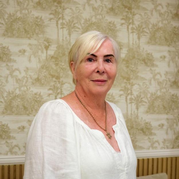 Portrait of a woman wearing a white blouse and necklace.