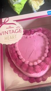 Pink heart-shaped cake in a box.