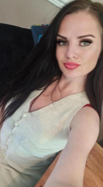 A woman with long dark hair looks at the camera.