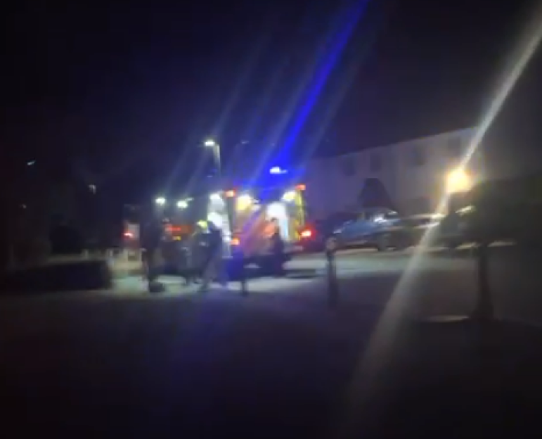 Nighttime scene with emergency responders near parked vehicles.