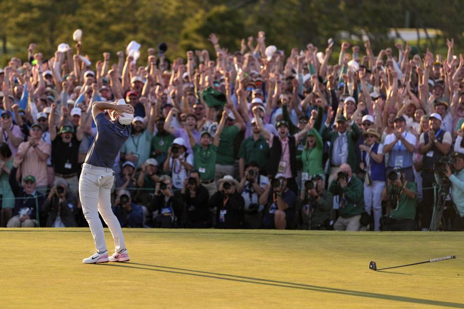 Rory McIlroy celebrates winning a golf tournament, cheered by a large crowd.