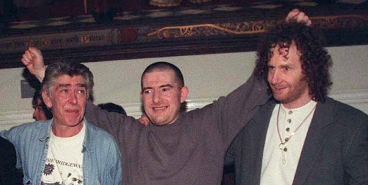 Three men smiling after having their sentences quashed.