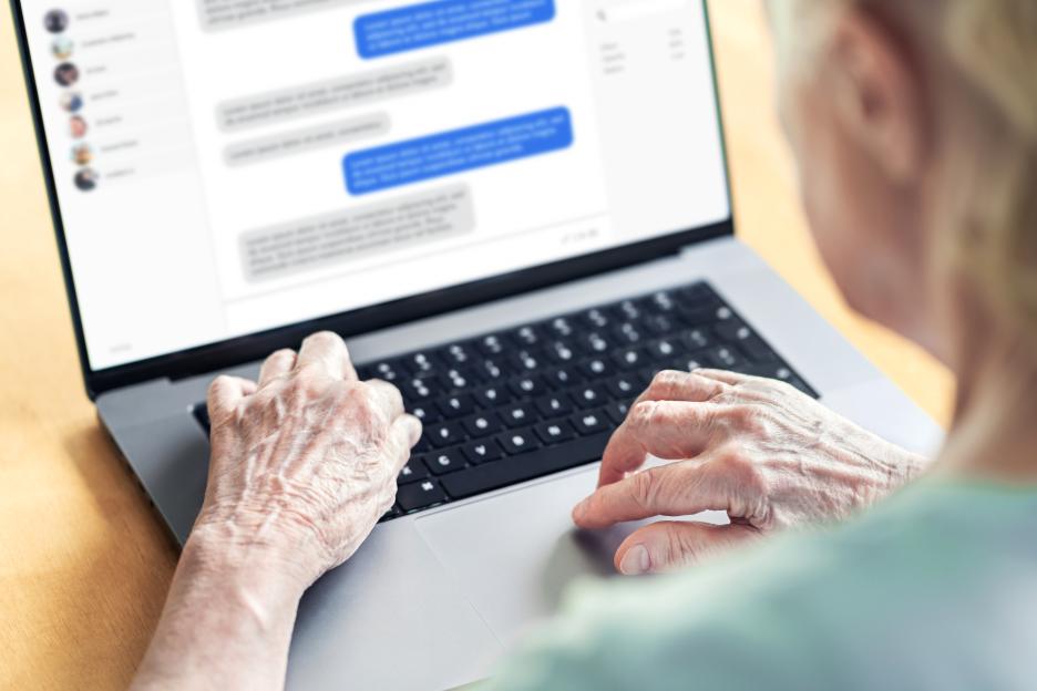 Older woman using a laptop to message online.