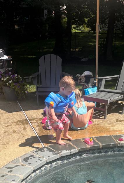 Toddler in flotation device by the pool.