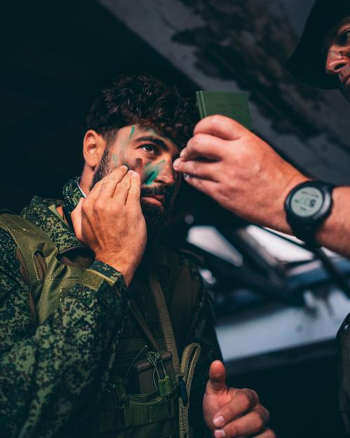 A soldier applying camouflage paint to his face.